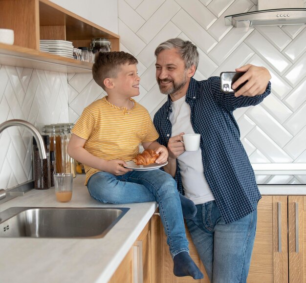 Medium shot father and kid taking selfies