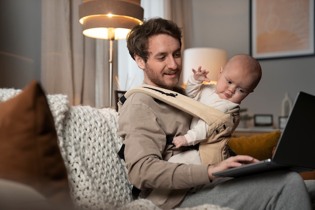 Medium shot father working while holding baby