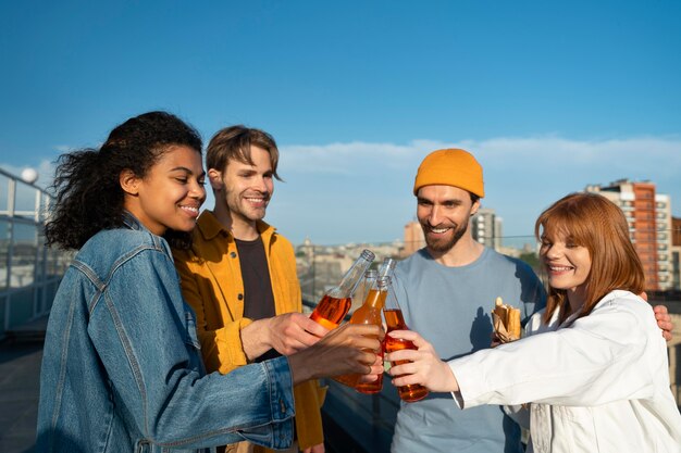 Medium shot friends clinking bottles