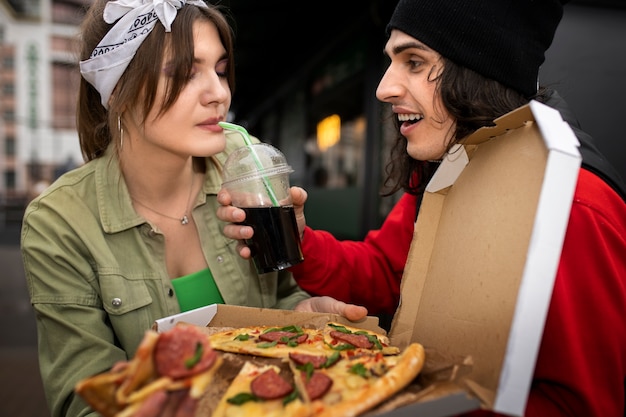 Free photo medium shot friends eating fast food in a funny way