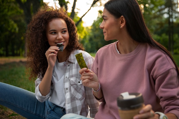 Free photo medium shot friends eating seaweed snacks