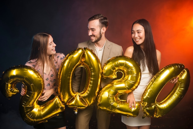 Free photo medium shot of friends holding balloons at new years party