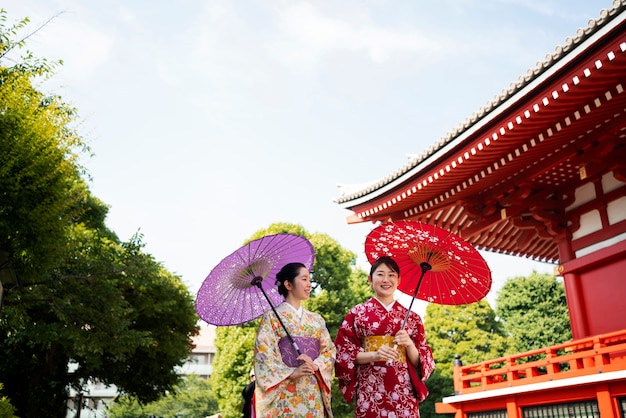 Medium shot friends holding wagasa umbrella