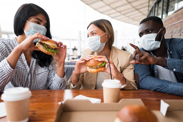 Medium shot friends wearing masks at table