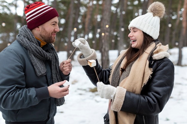 Free photo medium shot friends with marshmallows outdoors