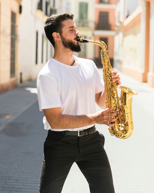 Medium shot front view musician playing saxophone in street