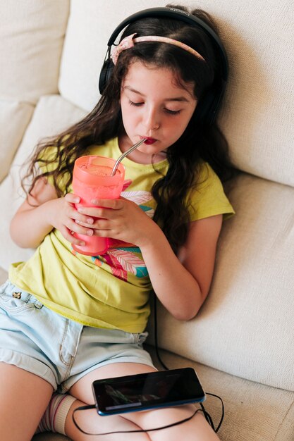 Medium shot girl drinking juice and looking at phone