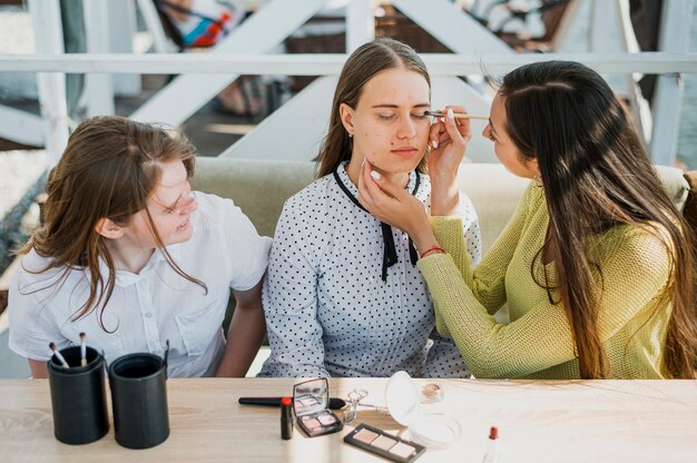 Medium shot girl getting make up from friend