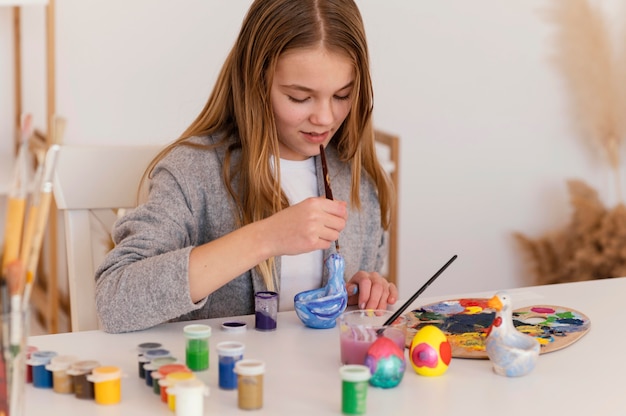 Medium shot girl painting object