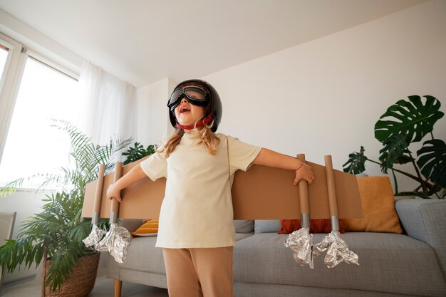 Medium shot girl playing with cardboard wings