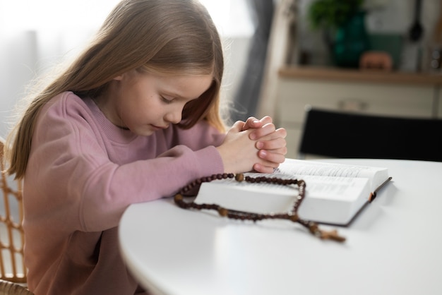 Medium shot girl praying at home