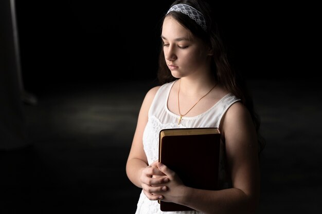 Medium shot girl praying with bible