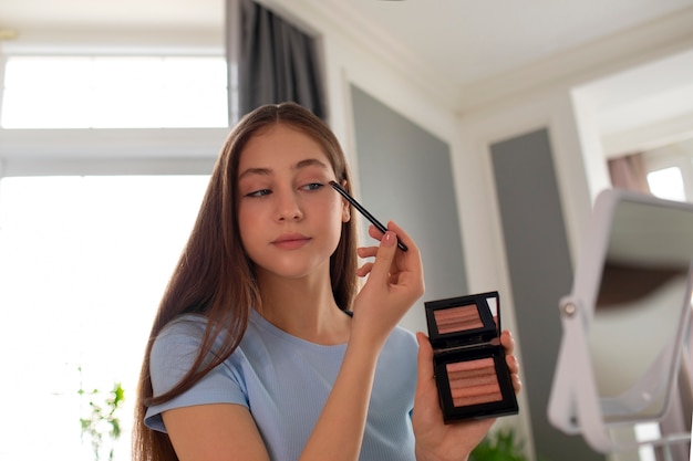 Free photo medium shot girl putting on makeup