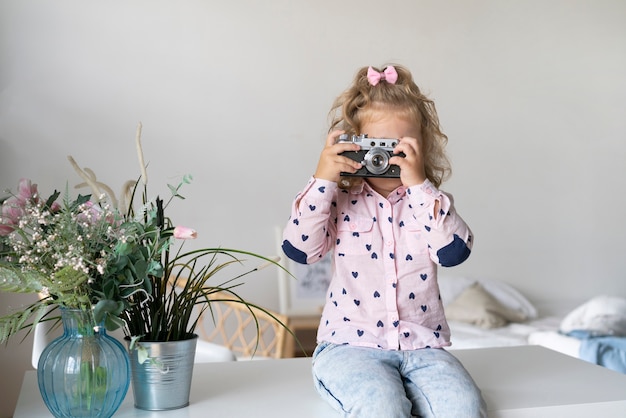 Free Photo medium shot girl with camera sitting on table