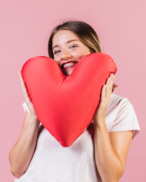 Free photo medium shot girl with heart shaped pillow