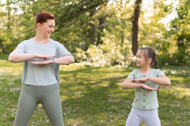 Medium shot girl and woman exercising together