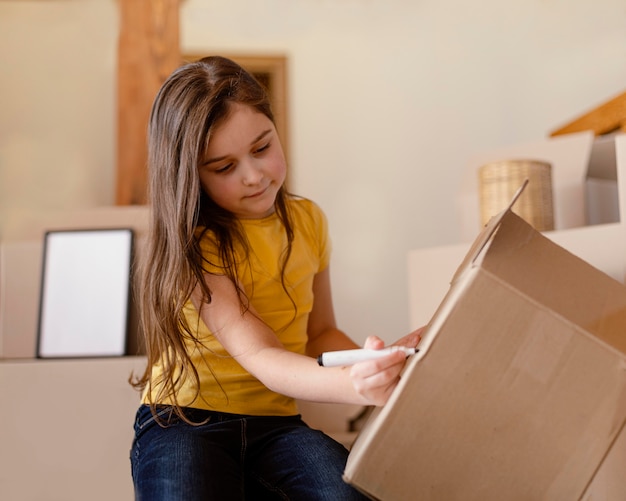 Free photo medium shot girl writing on box