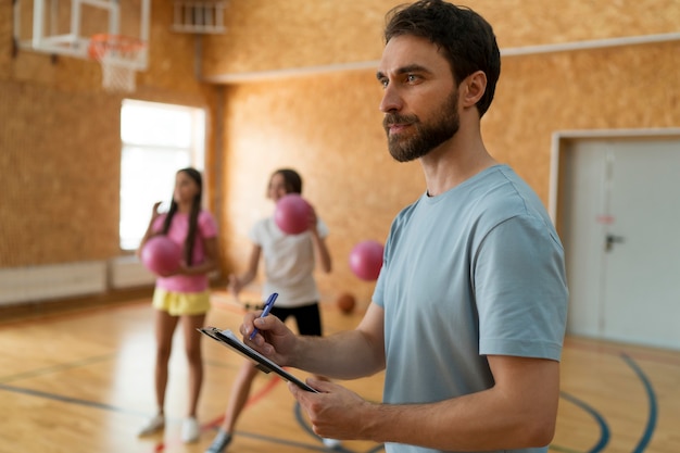 Medium shot girls and teacher at gym