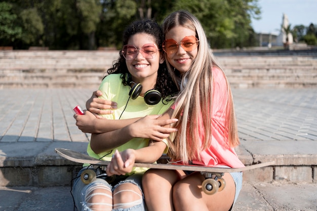 Free photo medium shot girls with skateboard sitting