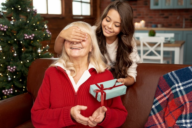 Medium shot granddaughter surprising grandma with gift