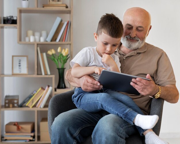 Medium shot grandfather with boy and tablet