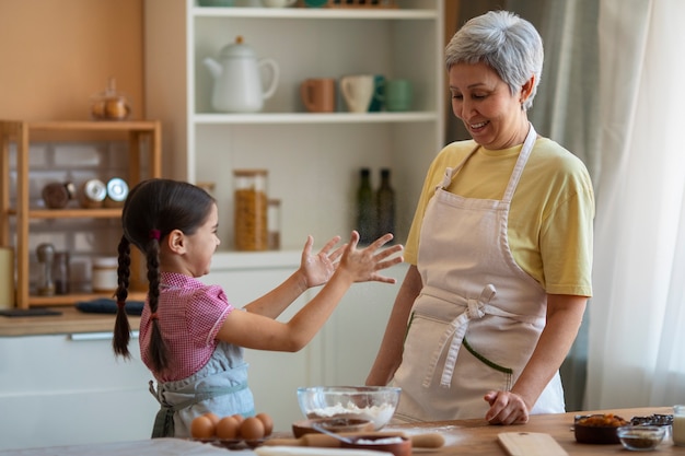 Free photo medium shot grandma and girl cooking together