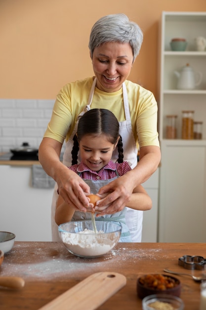 Free photo medium shot grandma and girl cooking together