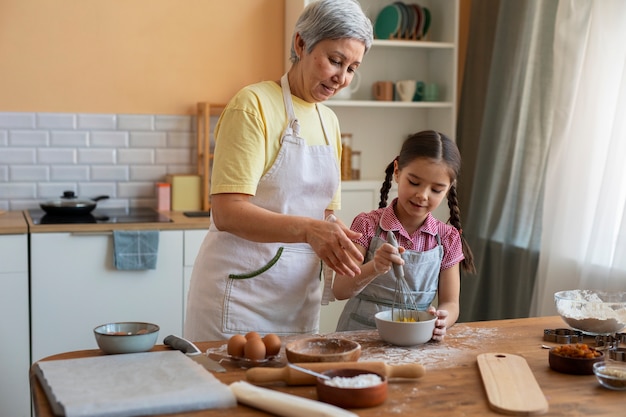 Free photo medium shot grandma and girl cooking together