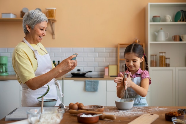 Free photo medium shot grandma and girl cooking together