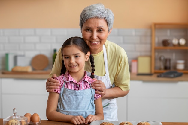 Free photo medium shot grandma and girl cooking together