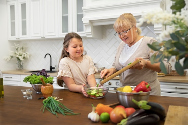 Free photo medium shot grandma and girl cooking