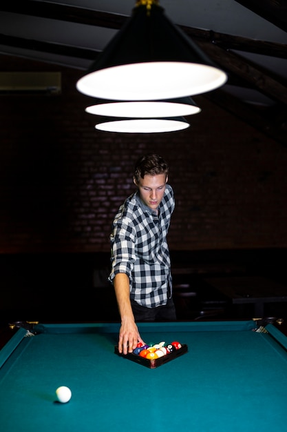 Free photo medium shot guy arranging balls with triangle