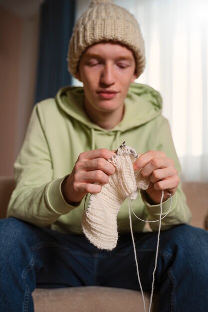 Medium shot guy knitting with white yarn