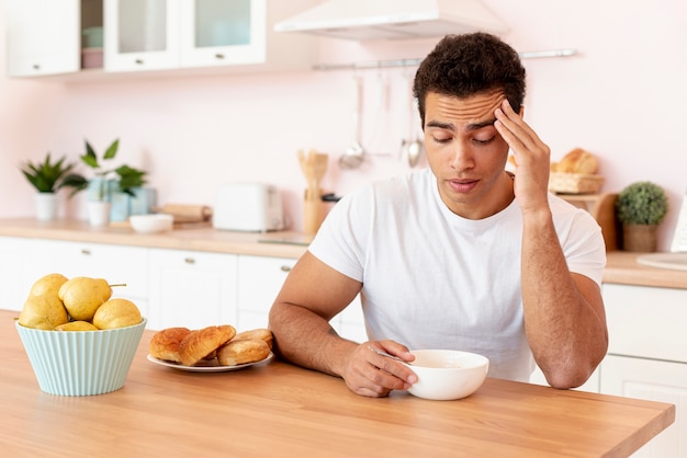 Medium shot guy with bowl of cereals in the kitchen