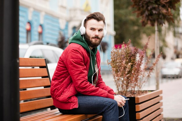 Medium shot guy with headphones and warm clothes