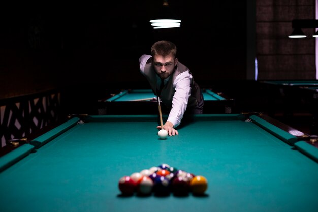 Medium shot guy with pool cue hitting white ball