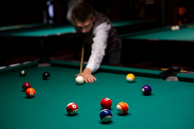 Free photo medium shot guy with pool cue playing billiard