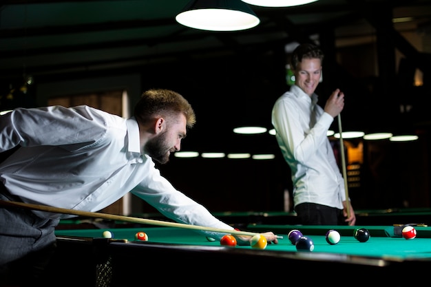 Medium shot guys playing billiard together