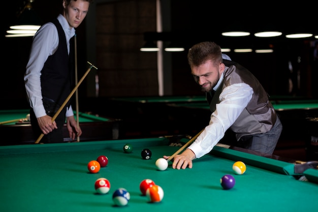 Medium shot guys playing billiard together 