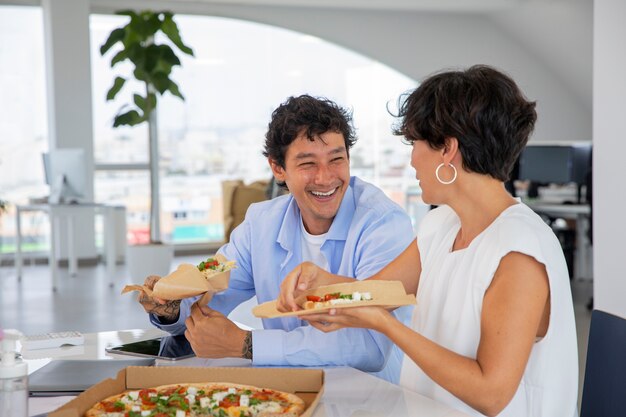 Medium shot happy colleagues with pizza