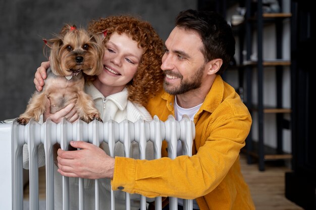 Medium shot happy couple and dog with heater