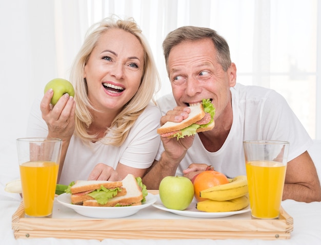 Medium shot happy couple eating healthy together