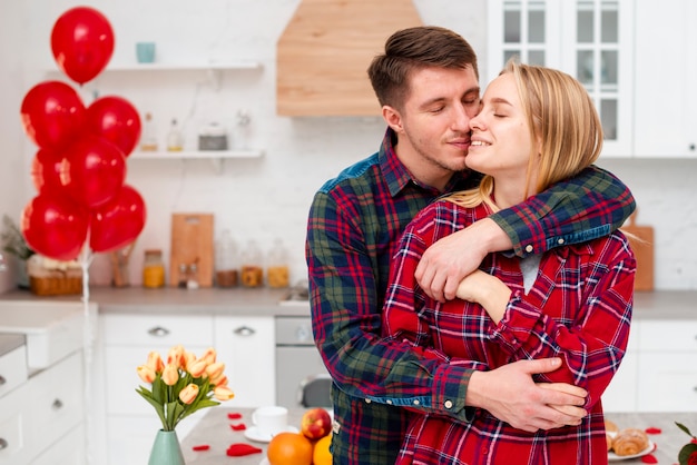 Medium shot happy couple hugging in the kitchen