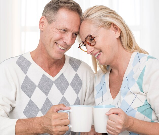 Free photo medium shot happy couple with mugs standing together