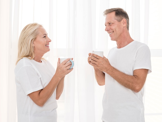 Free photo medium shot happy couple with mugs