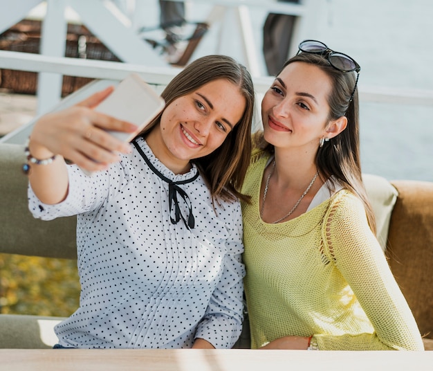 Medium shot happy friends taking a selfie