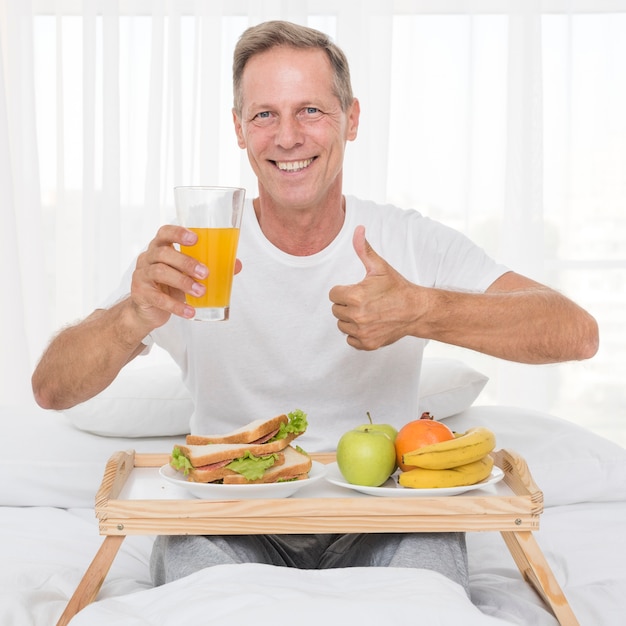 Medium shot happy man with juice showing approval