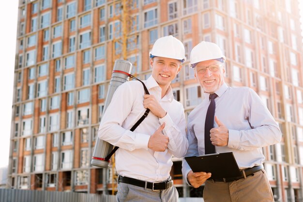 Medium shot happy men with helmets looking at camera