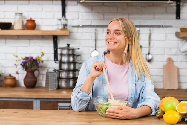 Free photo medium shot happy woman making a salad