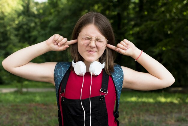 Medium shot of highschool girl covering her ears